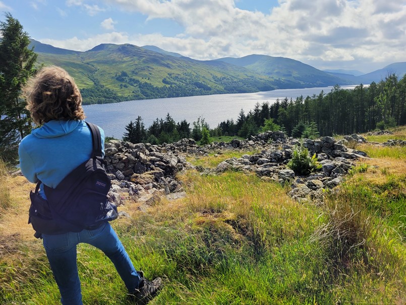 Young man viewing a Highland loch in the distance on a sunny day