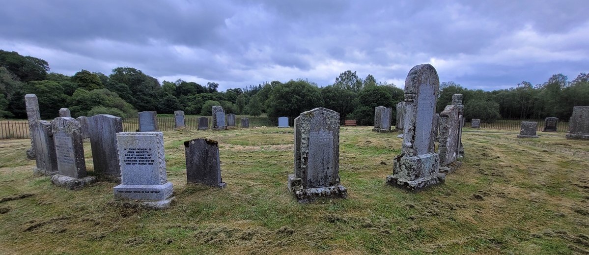 gravestones in a field under a cloudy sky